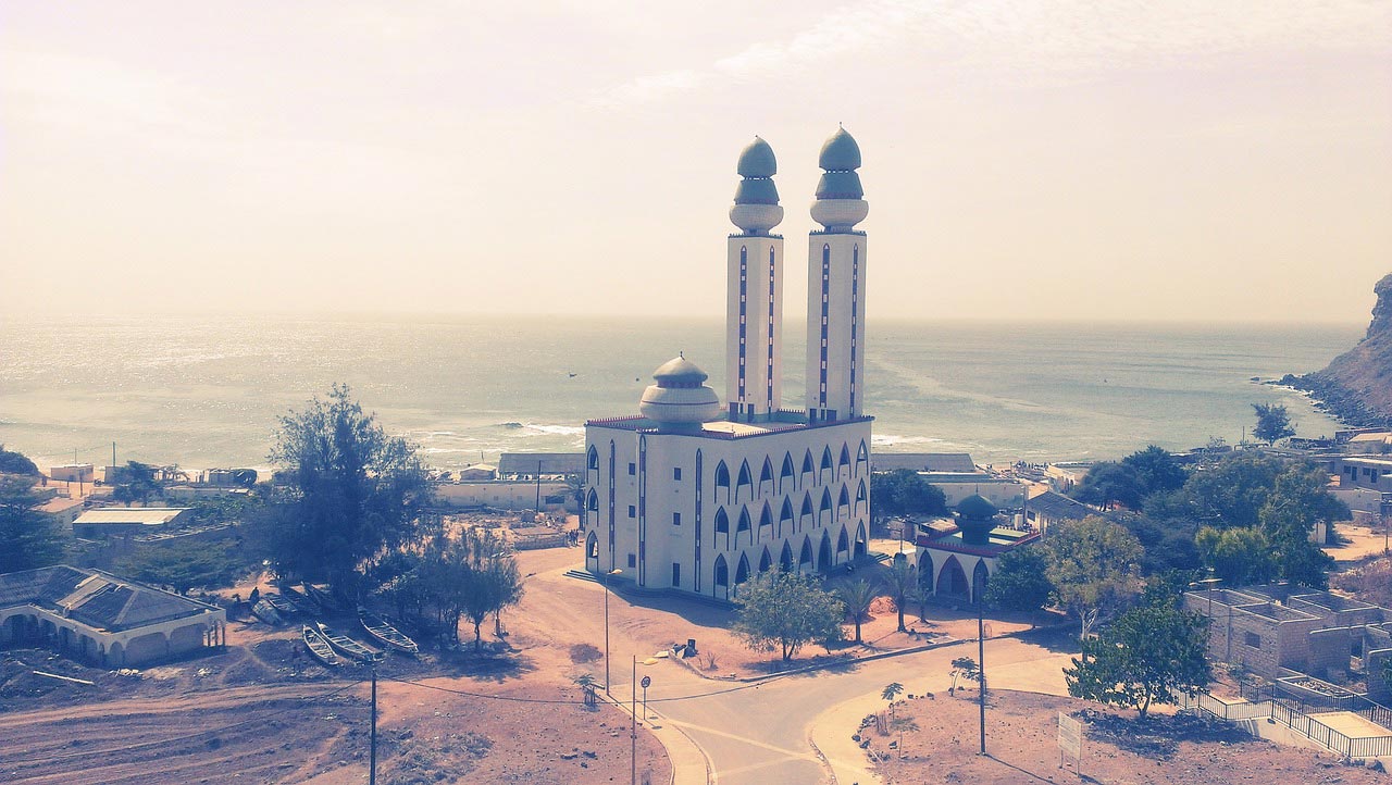 a large white building with two minaret 's in front of the ocean